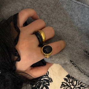 Dettaglio macro del set da tre pezzi con anelli dorati e agata nera sulla mano della modella