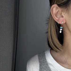 Close-up of colorful beaded earrings featuring a polished silver heart pendant on a model