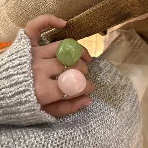 Close-up of translucent green and pink resin ball rings on hand with simple silver band