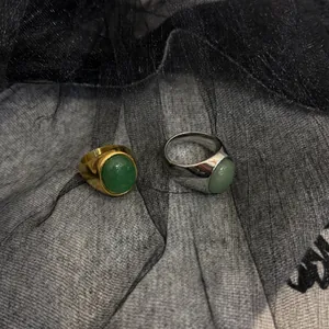 Dettaglio di anelli placcati oro e argento con pietre naturali ovali su sfondo di pizzo