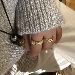 Nahaufnahme von goldenem Gitterring und gedrehtem Band mit Edelsteinkette