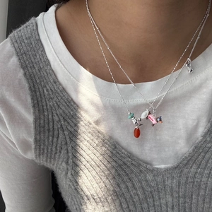 Detail of layered silver necklace with pink puppy and bird charms on a model