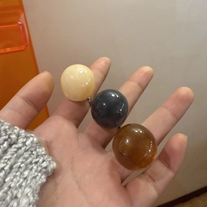 Close-up of three dome rings in beige, dark grey, and amber resin on silver bands