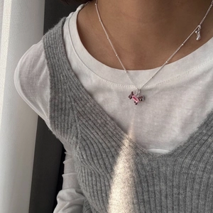 Detailed view of silver necklace with pink and brown puppy pendant and bone charm accessory