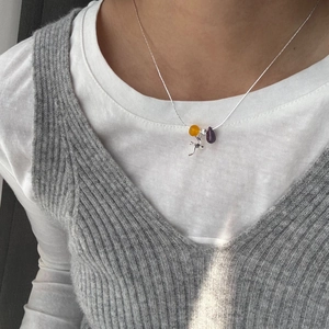 Detail of silver necklace with yellow agate bead, purple drop and magpie bird pendant