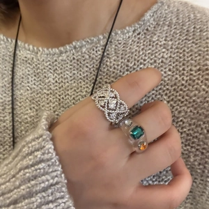 Details von Spitzen-Zirkonia-Ring und Kunstharz-Edelstein-Ring auf Hand mit Strickpullover