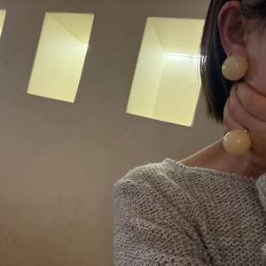 Macro shot of minimalist creamy yellow translucent resin dome stud earring on model