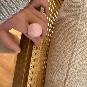 Close-up of a pink dome resin ring on hand with a warm and cozy home lifestyle setting