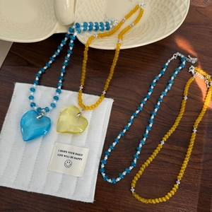Detail of colorful beaded necklaces with large translucent heart pendants in blue and yellow