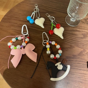 Close-up of four aesthetic bow and heart bag charms on a rustic wooden table background