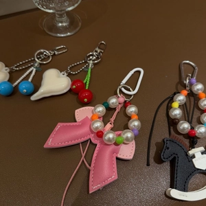 Detailed view of fashion bag charms with cherry pendants, leather bows and pearly beads
