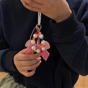 Detailed view of pink leather bow pendant with colorful pearl beads on a dark sweater