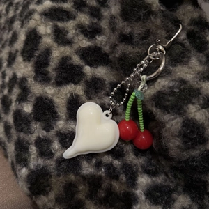 Detail view of heart and cherry charms with a silver clasp on leopard print fabric