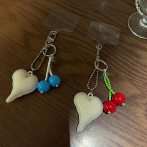 Detail of red and blue beaded cherry pendants with melting heart charms for phone cases