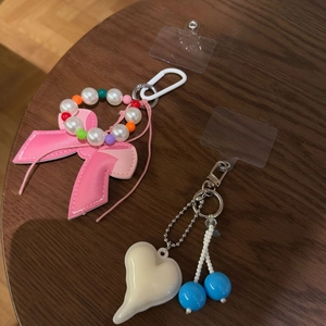 Pink leather bow and heart charm phone strap set with beads on a dark wooden background