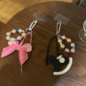 Detail view of pink leather bow phone strap with white pearls and colorful beads