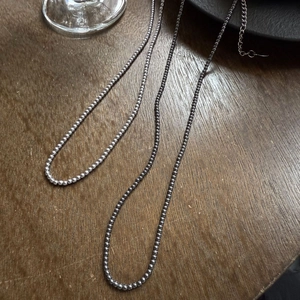 Gepolijste zilveren kralenketting set voor dames in een minimalistische stijl op hout