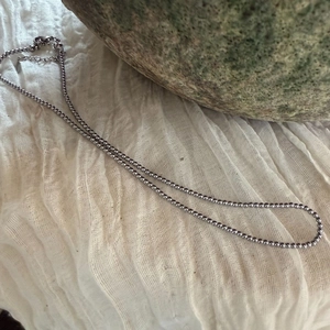 Detailopname van zilveren kogelketting met karabijnsluiting op een natuurlijke stenen ondergrond