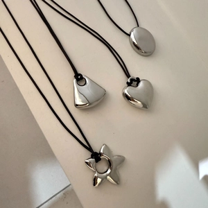 Detailed close-up of polished silver heart, star, and geometric pendants on black cords