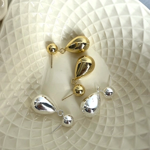 Gros plan de boucles d'oreilles goutte d'eau dorées et argentées au fini poli miroir brillant