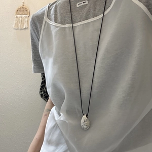 Long necklace with silver organic pendant on black cord shown on a model outfit