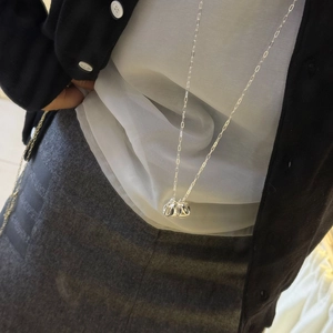 Detalle del collar largo para suéter con colgante de esfera metálica texturizada en cadena fina