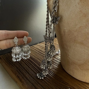 Close-up of Jhumka earrings and butterfly tassel accessory with pearls and rhinestones