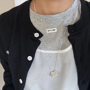 Detalle de collares plateados en capas con un colgante de mini bolso único en una cadena larga