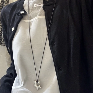 Detail of a minimalist silver star pendant with a black cord necklace on a casual outfit
