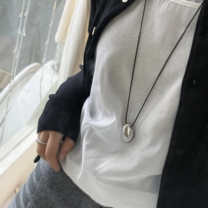 Detail view of a long heart pendant necklace with black cord and silver finish