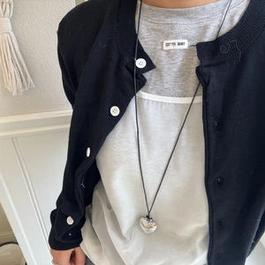 Detail of silver heart pendant necklace on model with layered black and grey clothing