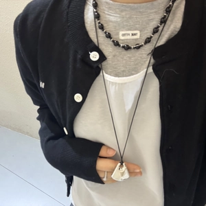 Close-up of layered black beaded choker and silver geometric pendant heart necklace
