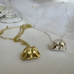 Detalle macro de collares mini bolso en oro y plata con elegante decoración blanca