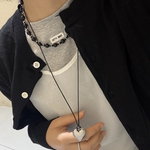 Close-up of layered heart pendant necklace with black cord and beaded chain on a model