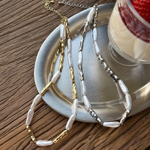 Detailed shot of baroque pearl necklace with metallic tubes on a silver tray