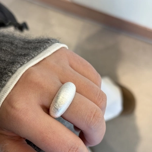Macro view showing the brushed metal texture of the silver dome ring on a model hand