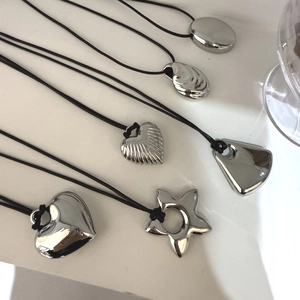 Macro shot of six assorted silver metal charms featuring heart, shell and star on black cords