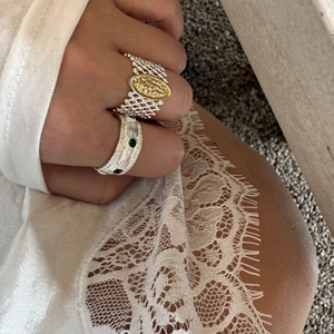 Italian brushed style lattice rings with gold relief and green gemstones on fingers