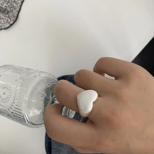 Retro matte white heart ring in brushed silver finish on model hand against glass