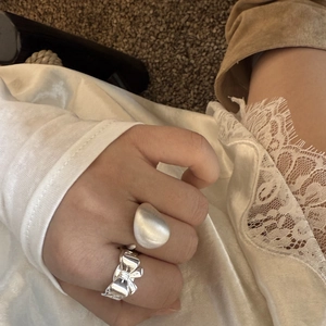 Italian brushed metal water-drop ring and polished bow ring set shown on hand