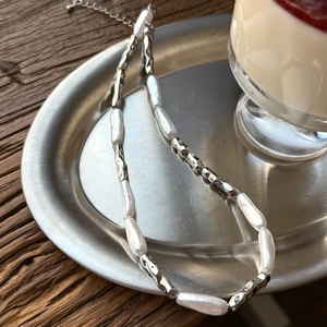 Detailed macro of baroque pearl necklace with irregular silver metallic tubes