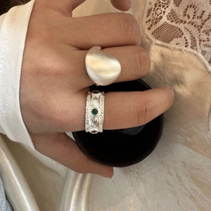 Detail of Italian style brushed silver ring set with vintage hollow pattern and green gemstone
