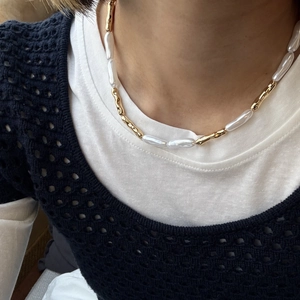 Detailed view of baroque pearl and gold textured tube necklace worn on collarbone