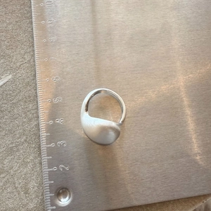 Detailed top view of a silver-tone brushed metal ring on a ruler measuring two centimeters