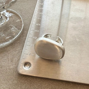 Detail shot of a brushed silver ring featuring a large pebble-shaped rectangular face