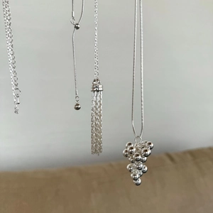 Close-up of silver grape pendant necklace with elegant adjustable snake chain tassels
