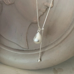 Detail of silver water-drop pendant with brushed texture and adjustable slider chain