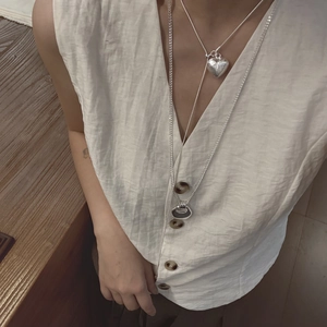 Detail of silver brushed heart and circle double layered necklace on linen clothing