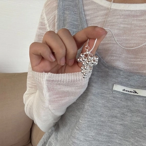 Close-up of a silver grape cluster pendant necklace on a long chain worn by a model