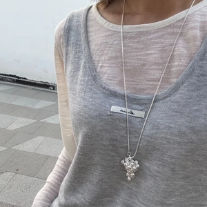 Close-up of silver long sweater necklace featuring a metallic grape bunch pendant on a model